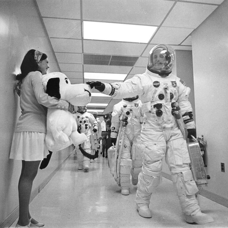 Astronaut touching a Snoopy teddy bear before departure